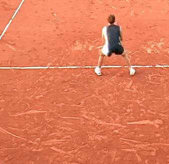 A Little Girl Is Playing Tennis On A Clay Court GIF