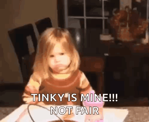 a little girl is sitting at a table and making a funny face and saying that tinky is mine !! not fair .