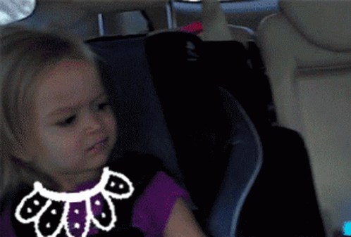 A Little Girl Is Sitting In A Car Seat With A Drawing Of A Cat On Her Shirt GIF