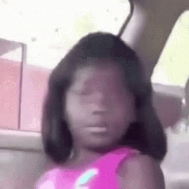 A Little Girl Is Sitting In A Car With Her Eyes Closed And Making A Funny Face . GIF