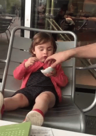 A Little Girl Is Sitting In A Chair Eating A Bowl Of Food GIF