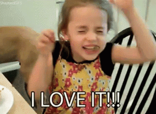 A Little Girl Is Sitting In A Chair With Her Arms In The Air And Saying I Love It . GIF