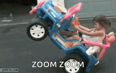 A Little Girl Is Sitting In A Toy Car With The Words Zoom Zoom Written On The Bottom . GIF