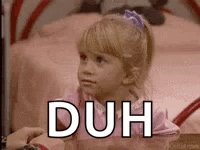 A Little Girl Is Sitting In Front Of A Bed With The Word Duh Written On Her Face . GIF