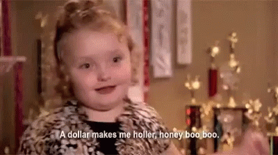 A Little Girl Is Sitting In Front Of A Christmas Tree And Talking About A Dollar Making Her Holler . GIF