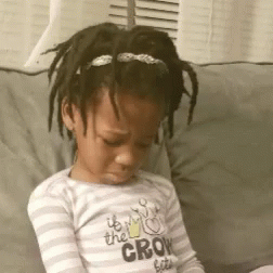 a little girl is sitting on a couch wearing a shirt that says " it 's the crow bites "