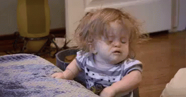 A Little Girl Is Sitting On A Couch With Her Eyes Closed And Making A Funny Face . GIF