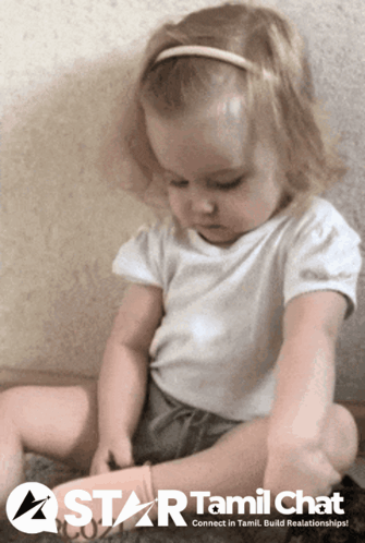 A Little Girl Is Sitting On The Floor With A Star Tamil Chat Logo In The Background GIF