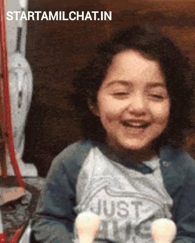 A Little Girl Is Smiling And Wearing A Shirt That Says Just Love GIF