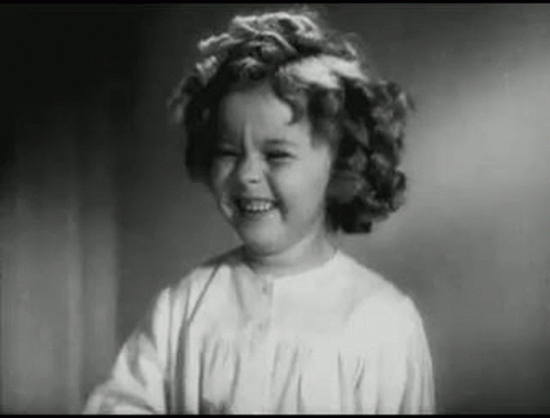 A Little Girl Is Smiling In A Black And White Photo . GIF