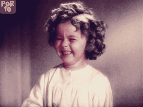 A Little Girl Is Smiling In Front Of A Sign That Says Por 10 On It GIF