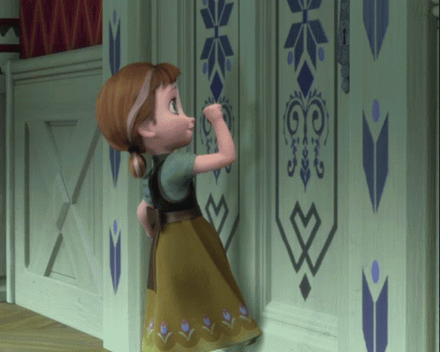 a little girl is standing in front of a wall with a geometric design