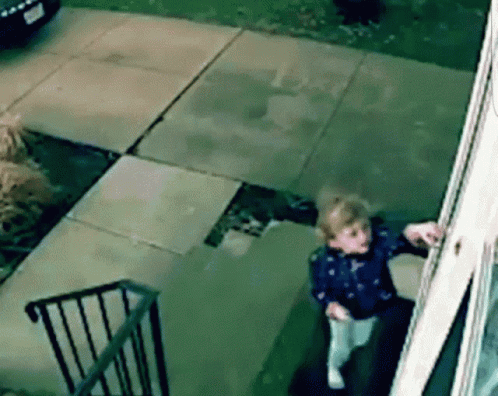 A Little Girl Is Standing On The Steps Of A Building Looking Out A Window GIF