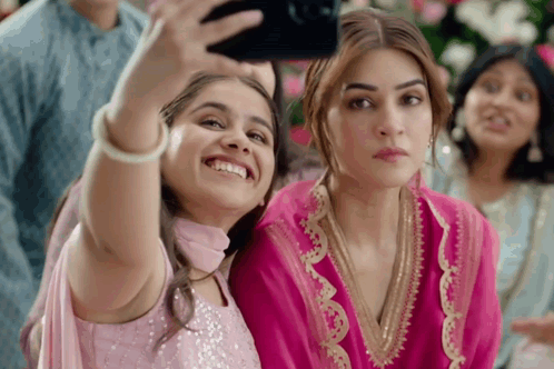 A Little Girl Is Taking A Selfie With A Woman In A Pink Dress GIF