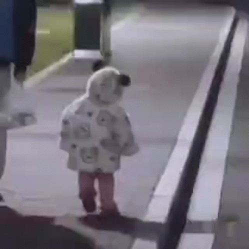 A Little Girl Is Walking Down A Sidewalk At Night Wearing A Sheep Costume . GIF
