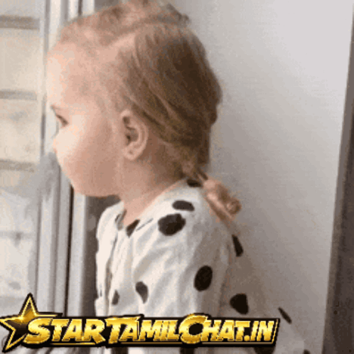 A Little Girl Looking Out A Window With A Star That Says Starttamilchat.in On It GIF