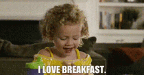 A Little Girl Says I Love Breakfast While Eating A Snack GIF
