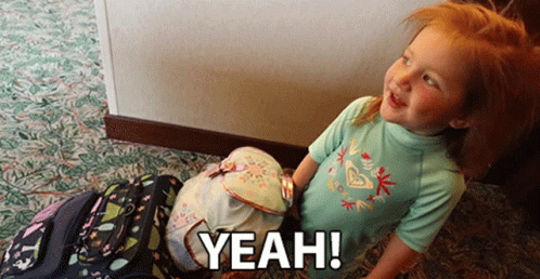 A Little Girl Standing Next To A Stack Of Backpacks With The Words Yeah Written On It GIF