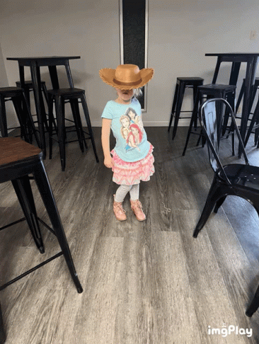 A Little Girl Wearing A Cowboy Hat And A Disney Shirt GIF