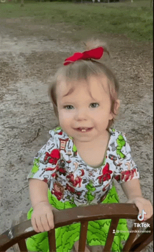 A Little Girl Wearing A Green And White Dress Is Sitting On A Chair With A Tiktok Watermark GIF