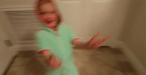 A Little Girl Wearing A Hoodie Is Standing In A Hallway GIF