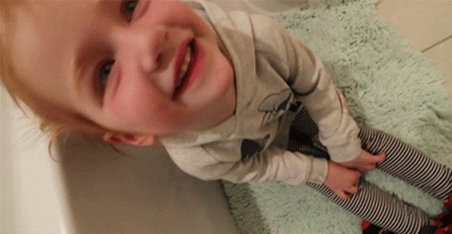 A Little Girl Wearing Striped Pants And A Shirt With A Bow On It GIF