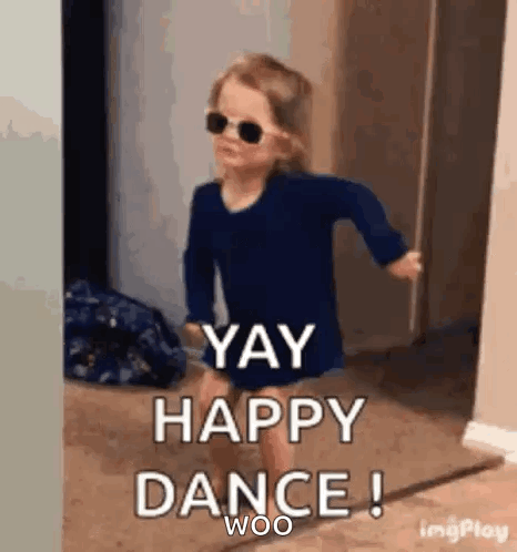 a little girl wearing sunglasses and a blue shirt is dancing in a hallway .