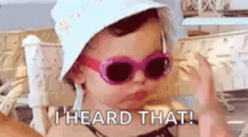 A Little Girl Wearing Sunglasses And A Hat Is Making A Funny Face . GIF