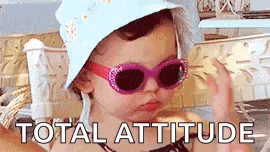 A Little Girl Wearing Sunglasses And A Hat With The Words `` Total Attitude '' Written Above Her . GIF