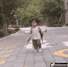 A Little Girl With A Backpack Is Walking Down A Brick Road .. GIF