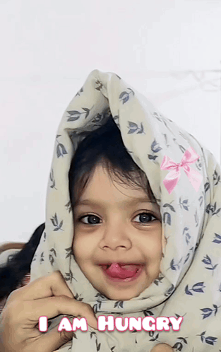 A Little Girl With A Blanket On Her Head And The Words I Am Hungry On The Bottom GIF