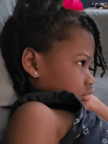 A Little Girl With A Pink Bow In Her Hair Looks To The Side GIF