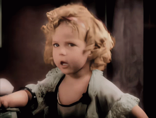 A Little Girl With Curly Blonde Hair Is Wearing A White Lace Top GIF