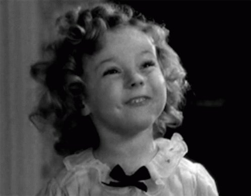 A Little Girl With Curly Hair Is Wearing A Bow Tie GIF