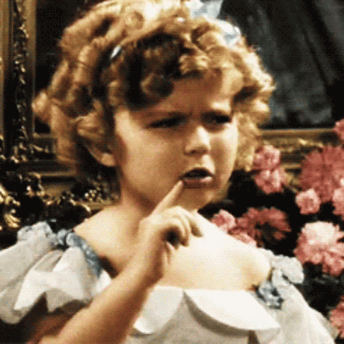 A Little Girl With Curly Hair Is Wearing A White Dress With Blue Ruffles GIF