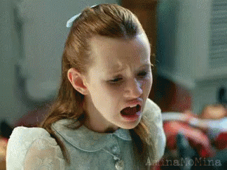 A Little Girl With Red Hair Is Making A Funny Face With Her Mouth Open . GIF