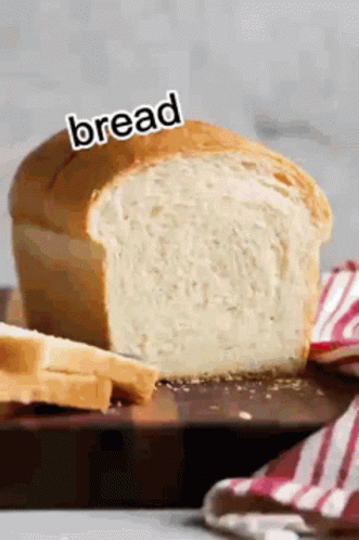 A Loaf Of Bread Is Sitting On A Wooden Cutting Board With A Knife . GIF