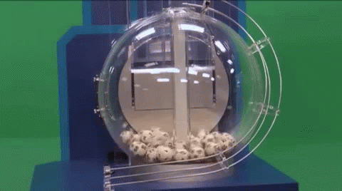 A Lottery Machine Filled With Balls And A Green Background GIF