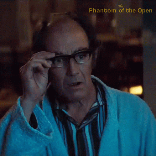 A Man Adjusts His Glasses With The Phantom Of The Open Written On The Bottom GIF