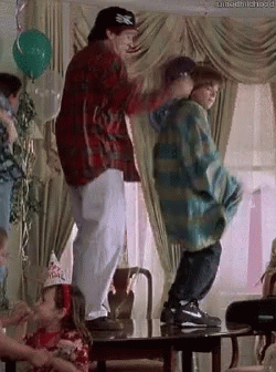 A Man And A Boy Are Dancing In A Living Room . GIF
