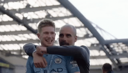 A Man And A Boy Are Hugging Each Other And Smiling . GIF