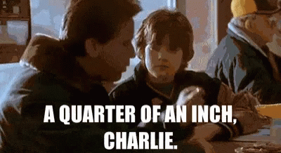 A Man And A Boy Are Sitting At A Table With The Words " A Quarter Of An Inch Charlie " On The Bottom GIF