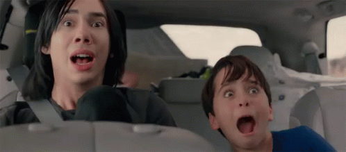 A Man And A Boy Are Sitting In The Back Seat Of A Car Making Funny Faces . GIF