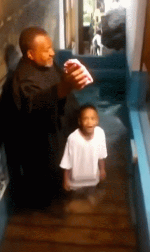 A Man And A Boy Are Standing In A Hallway And The Boy Is Wearing A White Shirt GIF