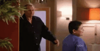 A Man And A Boy Are Standing In A Room . GIF