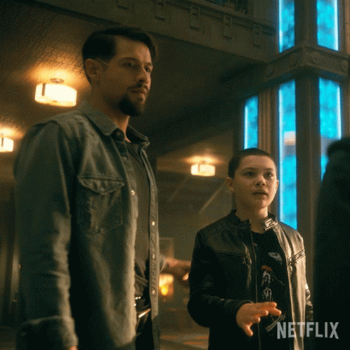 A Man And A Boy Standing Next To Each Other With A Netflix Logo Behind Them GIF
