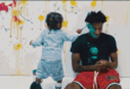 A Man And A Child Are Playing With Paint On A White Wall . GIF