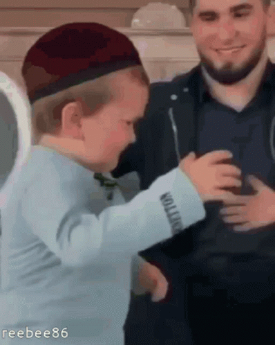 A Man And A Child Are Standing Next To Each Other . The Child Is Wearing A Hat And A Blue Shirt . GIF