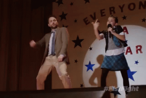 A Man And A Girl Are Dancing In Front Of A Sign That Says " Everyone " GIF