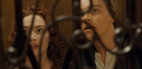 A Man And A Woman Are Behind A Fence And The Woman Is Giving The Middle Finger GIF